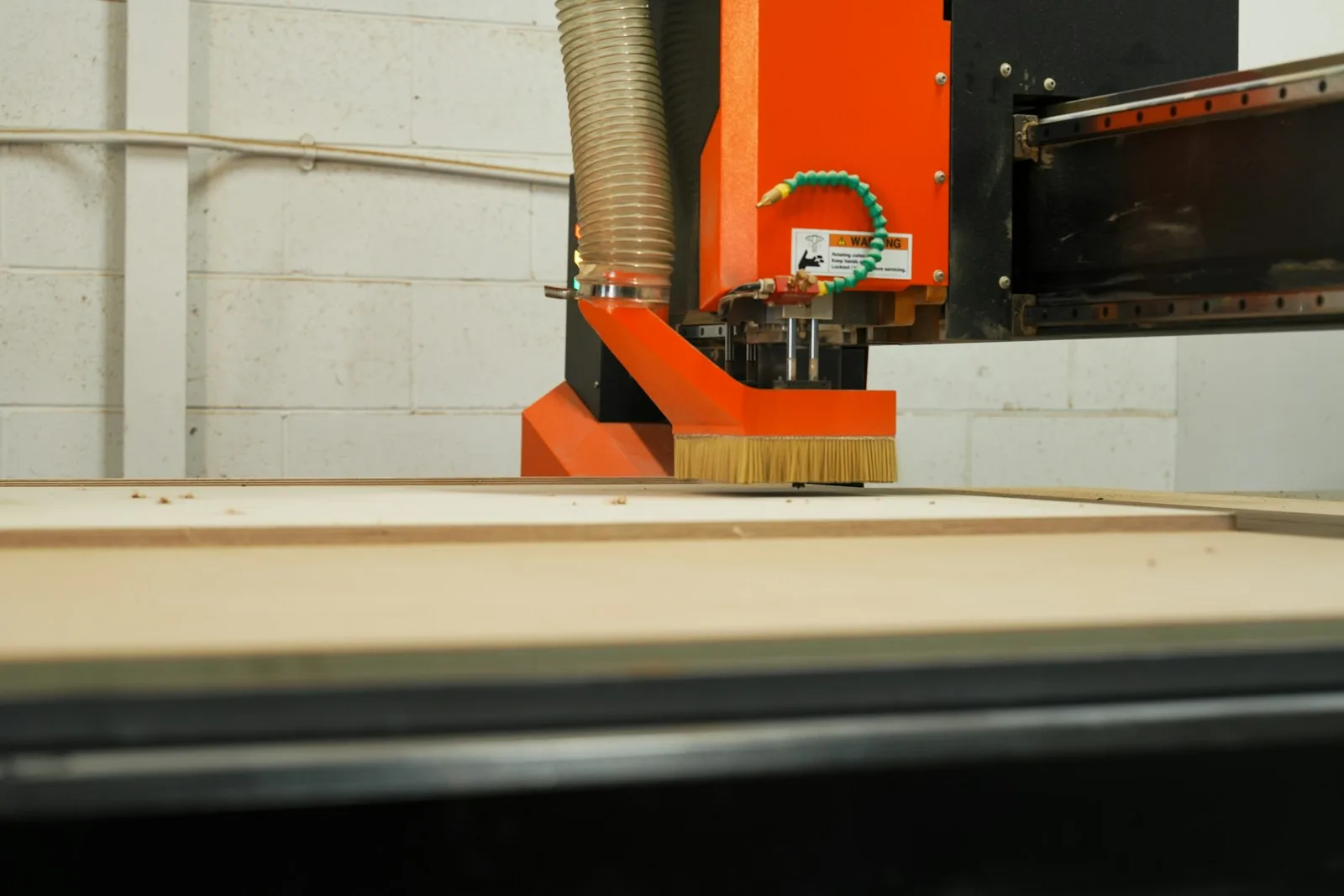 Fresadora CNC con cepillo trabajando un tablero de madera.