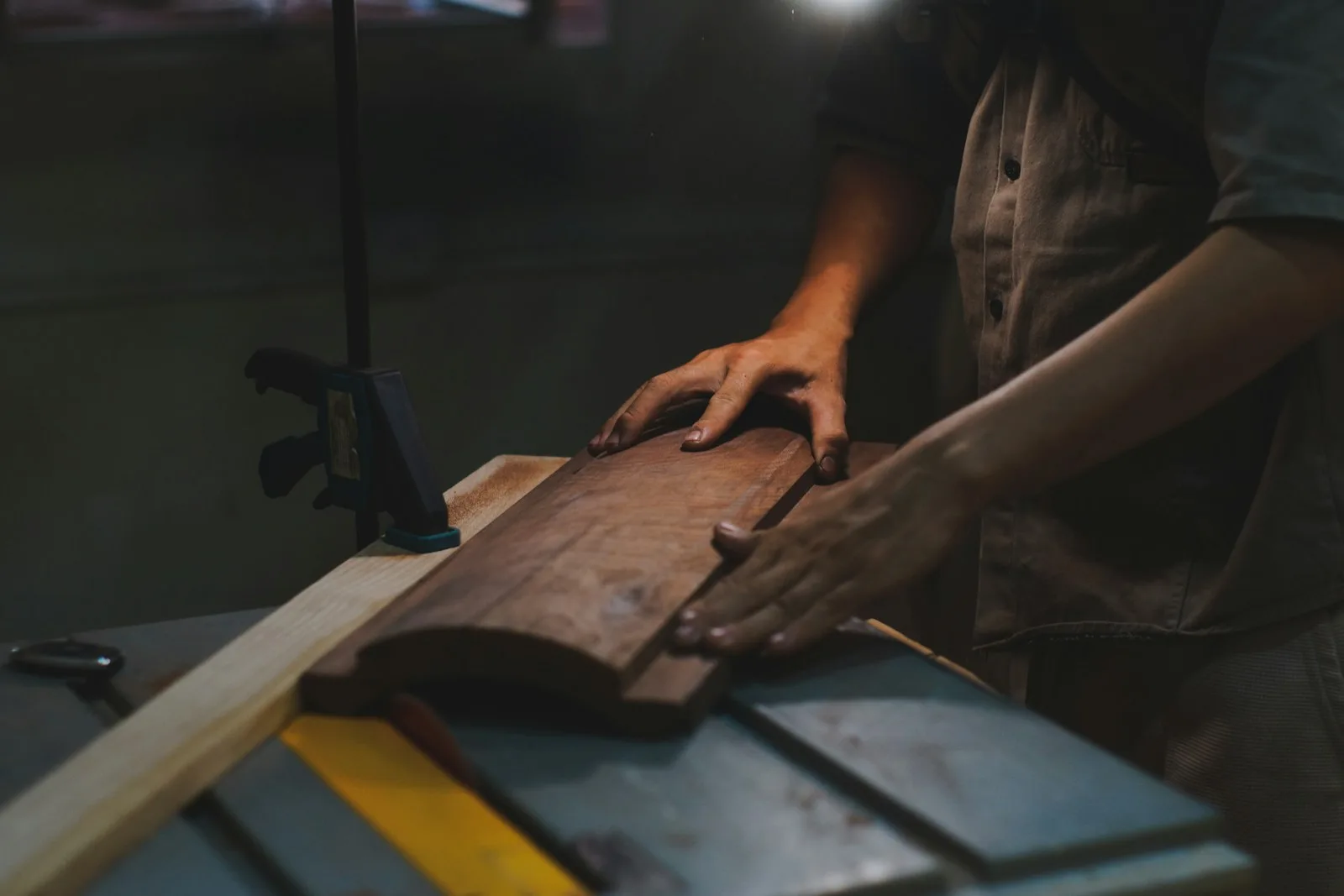 Manos guiando una pieza de madera en una sierra de mesa.