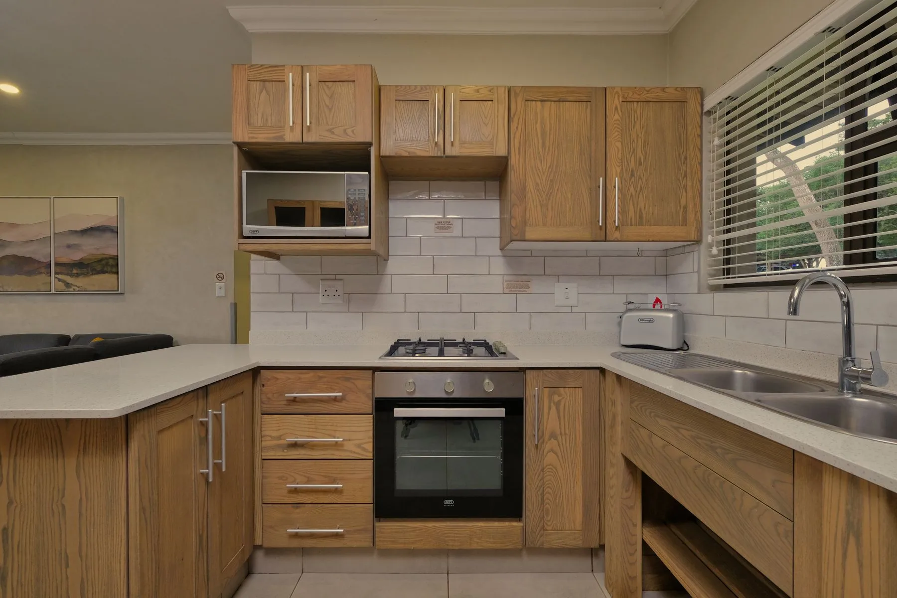 Cocina con armarios de madera, encimera clara y electrodomésticos integrados.