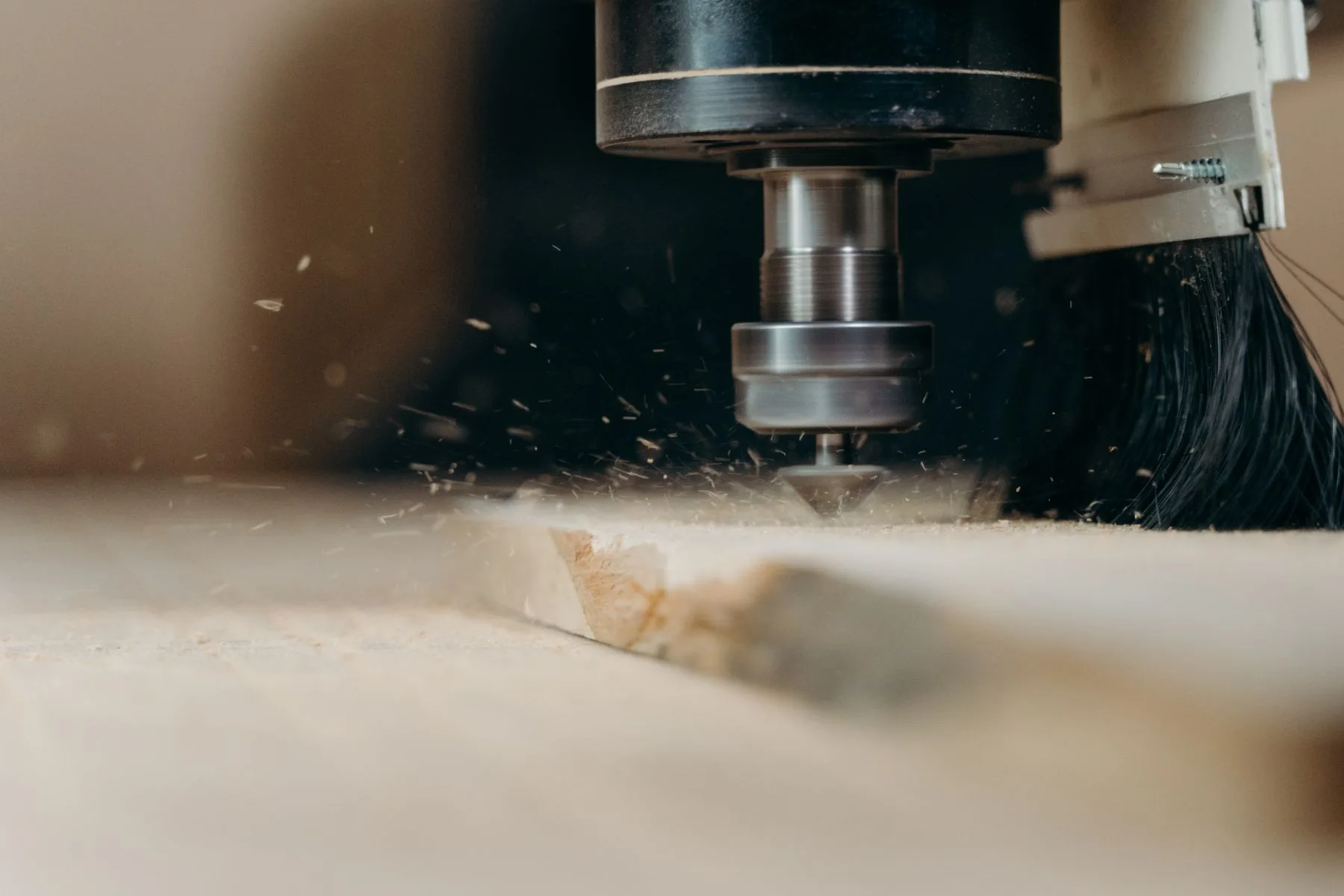 Fresa de una máquina cortando madera, con virutas visibles junto a la herramienta.